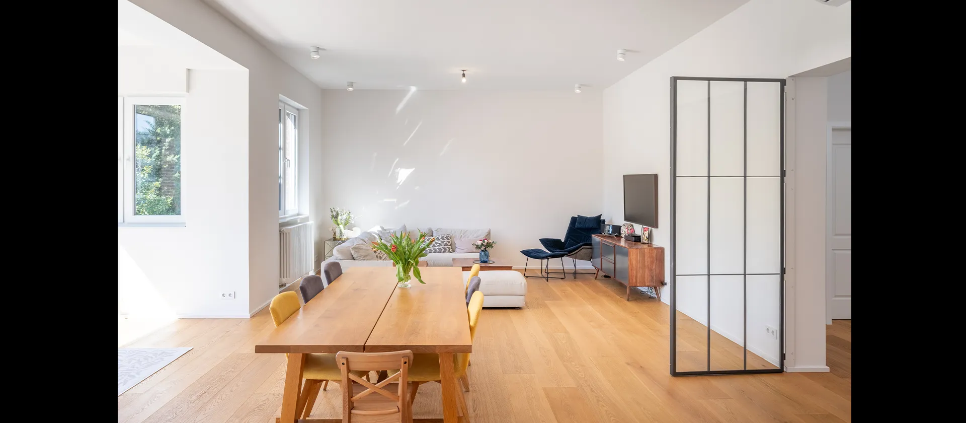 Offener Wohn- und Essbereich mit Massivholztisch und Glas-Schiebetür, harmonisch verbunden mit der modernen Küche von MTB Schreinerei.