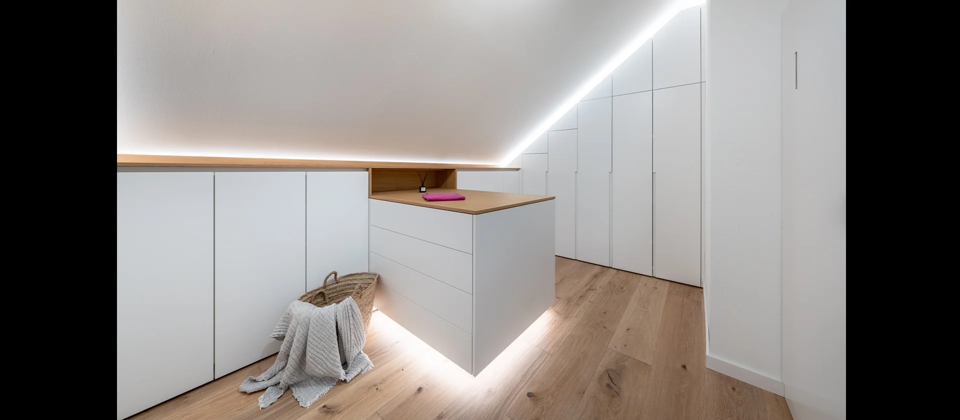 Weißer Einbauschrank unter Dachschräge mit LED-Beleuchtung und Schubladenelement auf Eichenboden